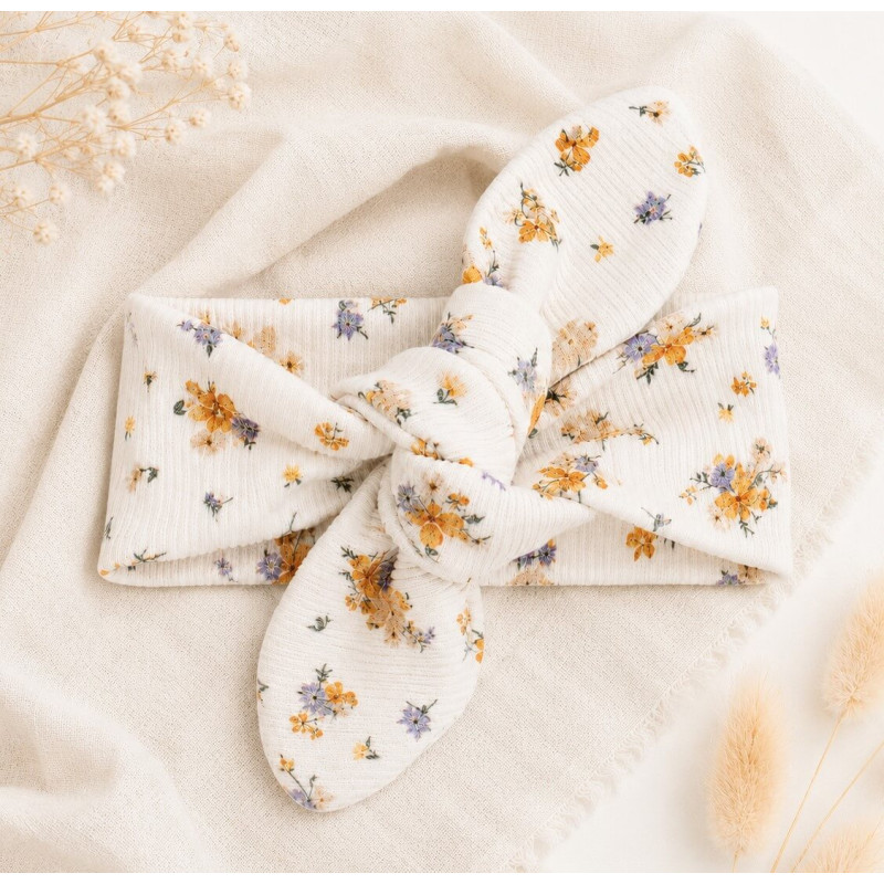 Een newborn haarbandje met kleine gele en blauwe bloemetjes in een dunne ribstof.