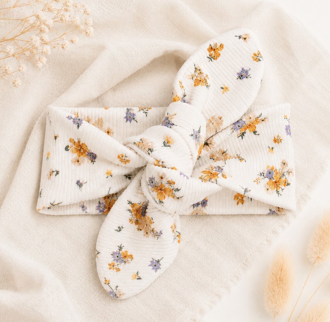 Een newborn haarbandje met kleine gele en blauwe bloemetjes in een dunne ribstof.