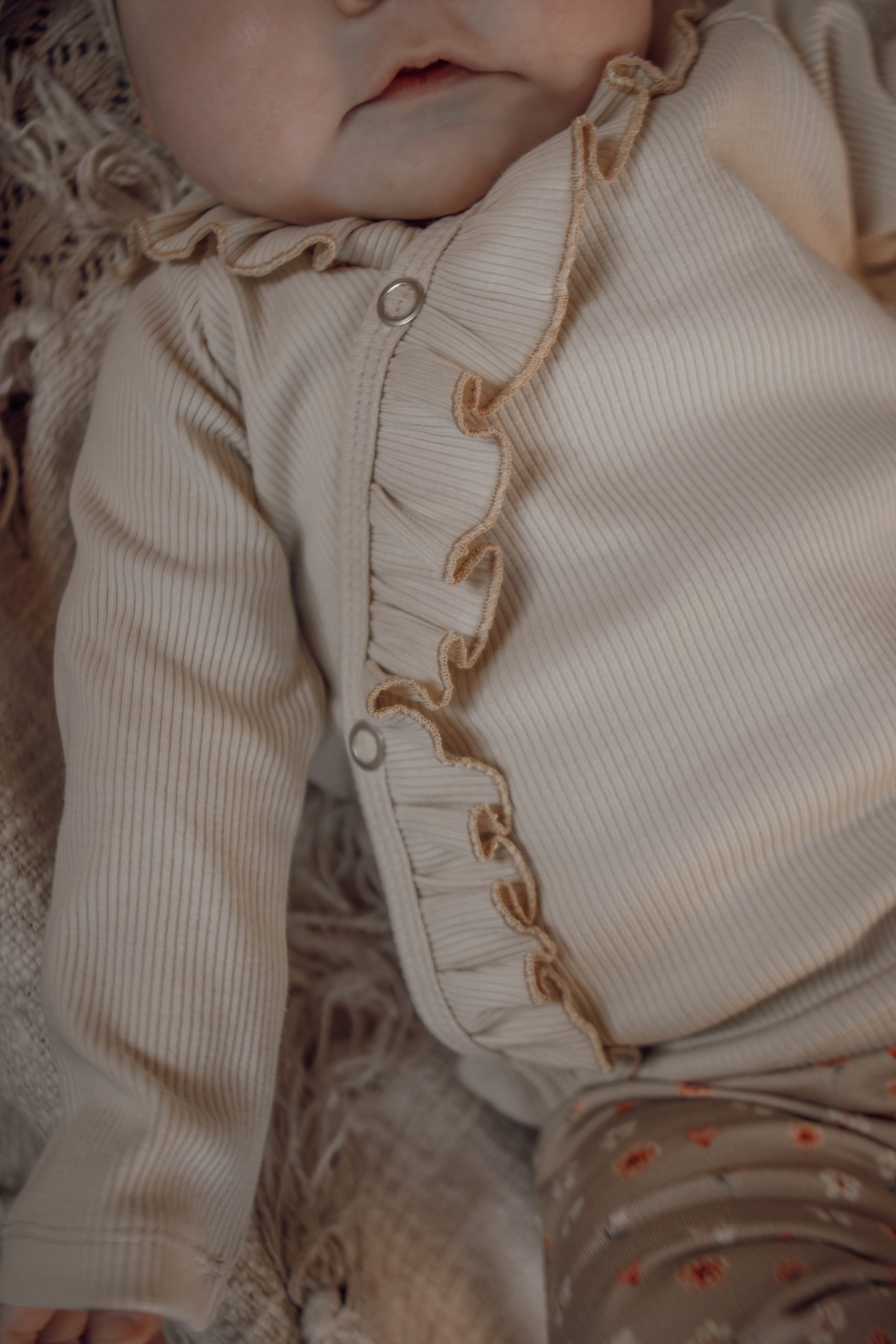 Newborn overslagshirtje met ruffles in een naturelkleur.