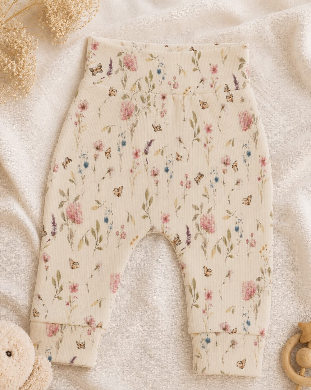 Een newborn ecru broekje met gekleurde bloemen.